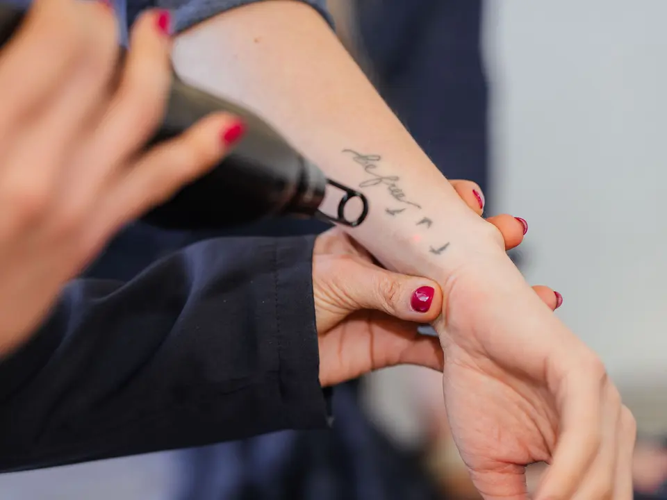 Laser handpiece removing a small tattoo on a client’s wrist